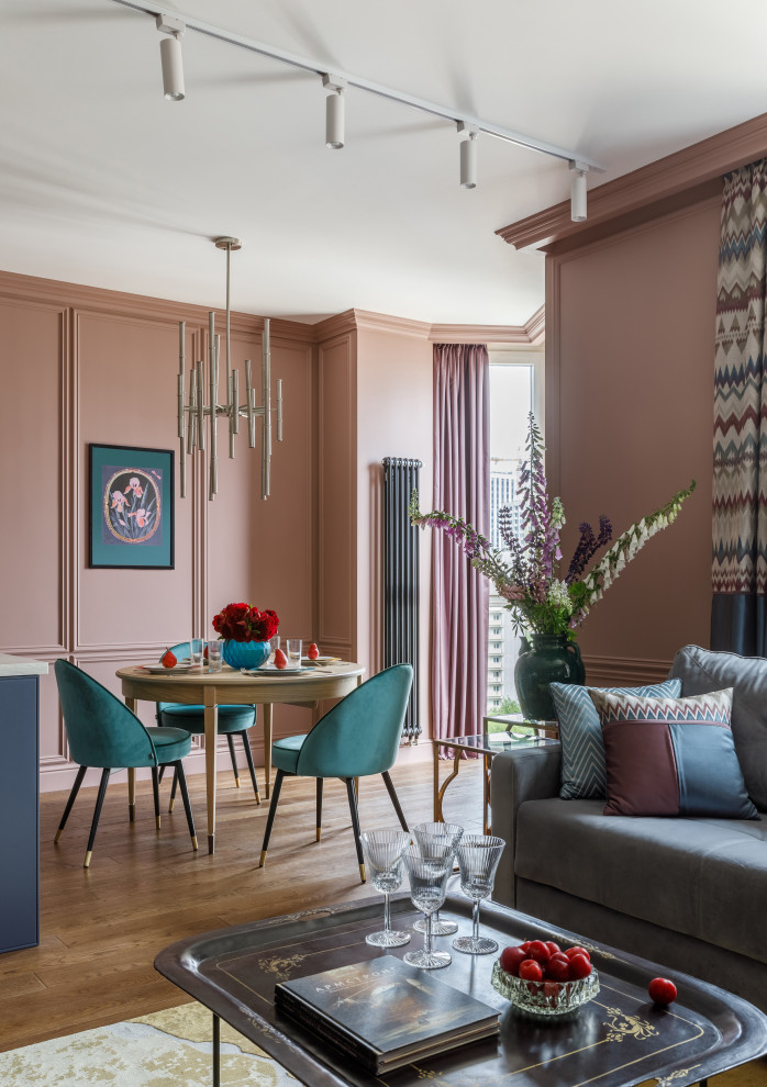 Immagine di una sala da pranzo aperta verso la cucina contemporanea con pareti rosa e pavimento in legno massello medio