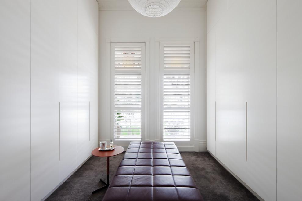 Modern gender neutral walk-in wardrobe in Melbourne with flat-panel cabinets, white cabinets, carpet and brown floors.