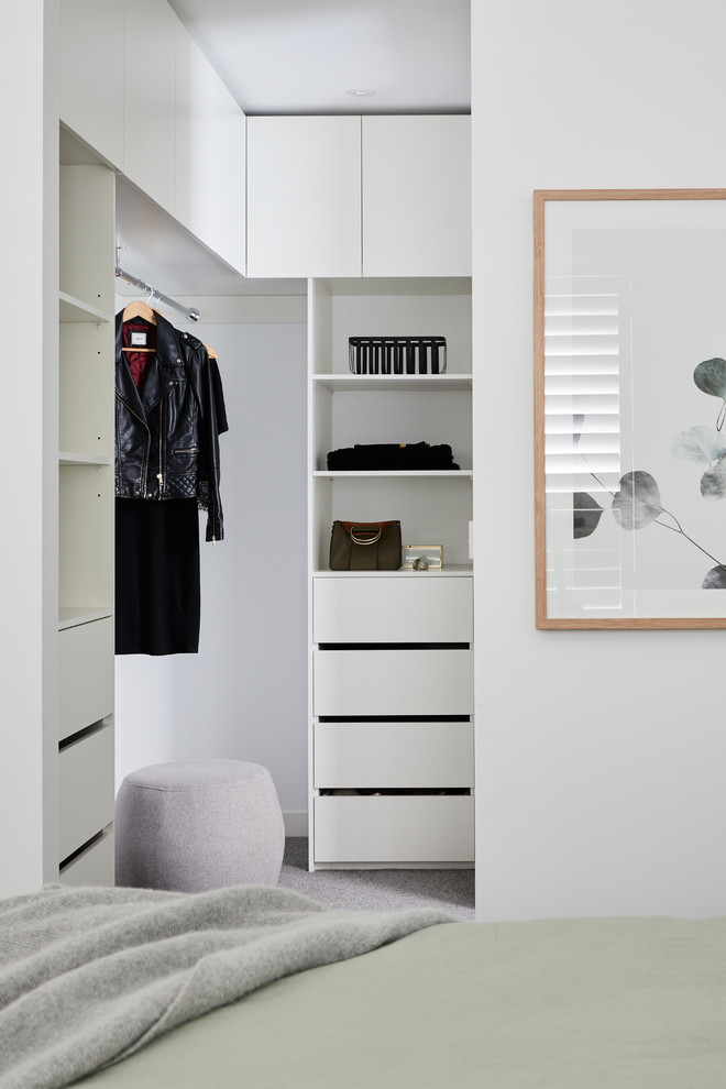 На фото: маленькая гардеробная комната унисекс в скандинавском стиле с белыми фасадами, ковровым покрытием и серым полом для на участке и в саду