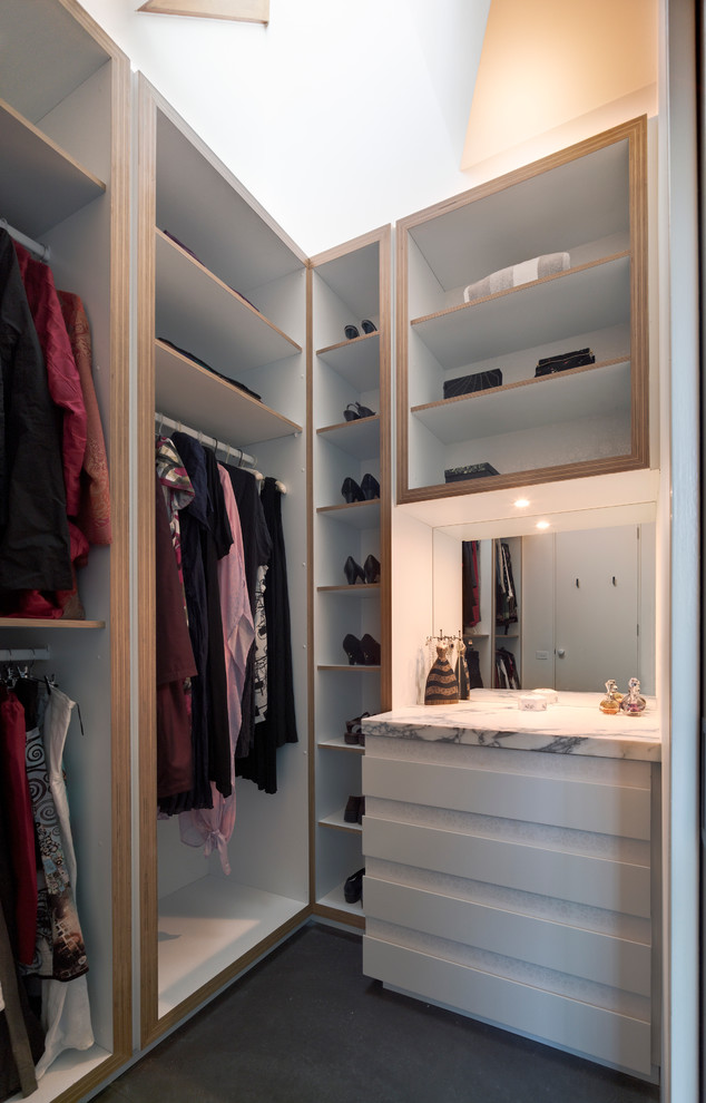 Diseño de armario vestidor de mujer contemporáneo pequeño con armarios con paneles lisos, puertas de armario blancas y suelo de cemento