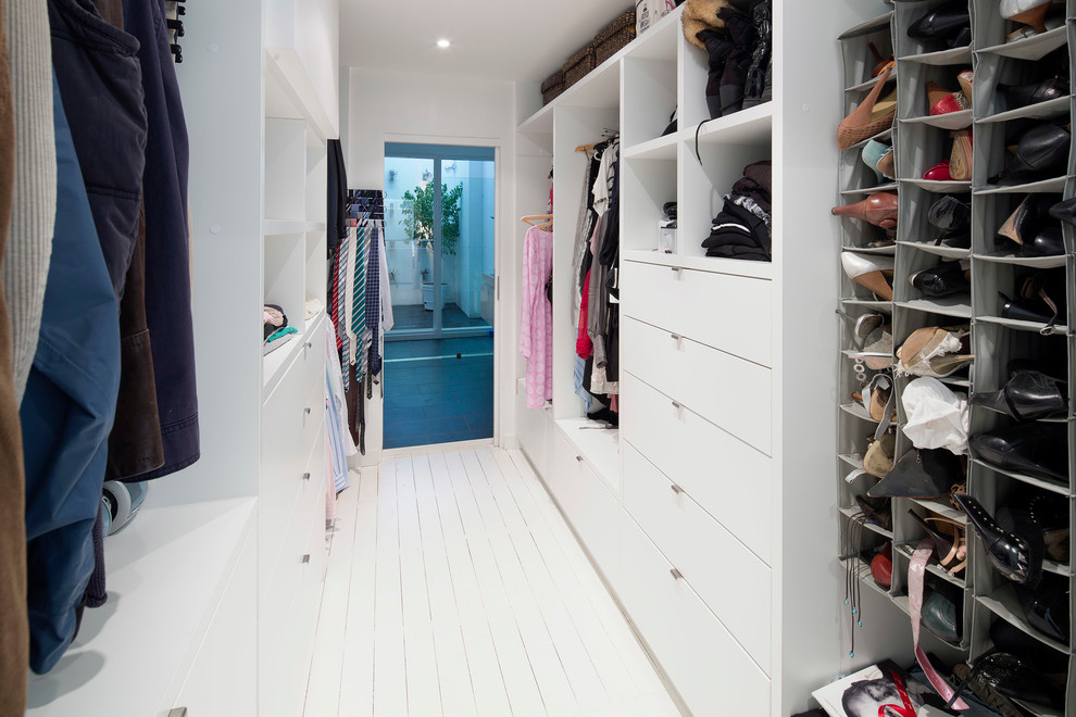 Modelo de armario vestidor unisex actual de tamaño medio con suelo de madera pintada, puertas de armario blancas, armarios con paneles lisos y suelo blanco