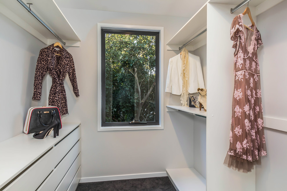 Modelo de armario vestidor unisex actual de tamaño medio con armarios con paneles lisos, puertas de armario blancas y moqueta