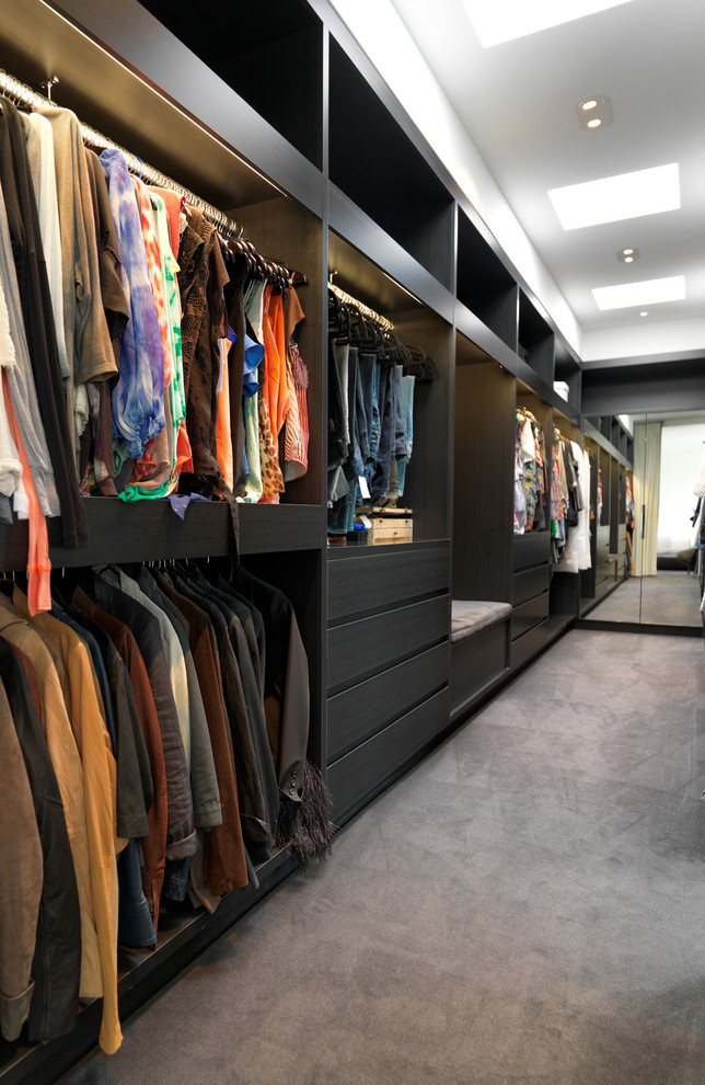 Modern inredning av ett stort walk-in-closet för män, med öppna hyllor, svarta skåp och heltäckningsmatta