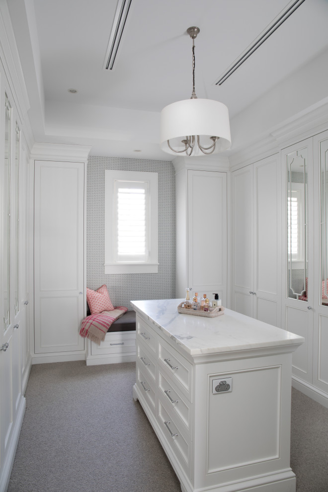 На фото: гардеробная комната унисекс в классическом стиле с фасадами в стиле шейкер, белыми фасадами и ковровым покрытием