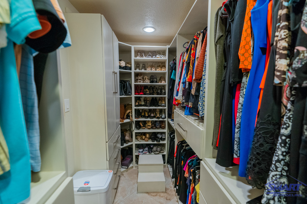 Modelo de armario vestidor de mujer de estilo americano pequeño con armarios con paneles lisos, puertas de armario blancas, suelo de baldosas de porcelana, suelo beige y casetón