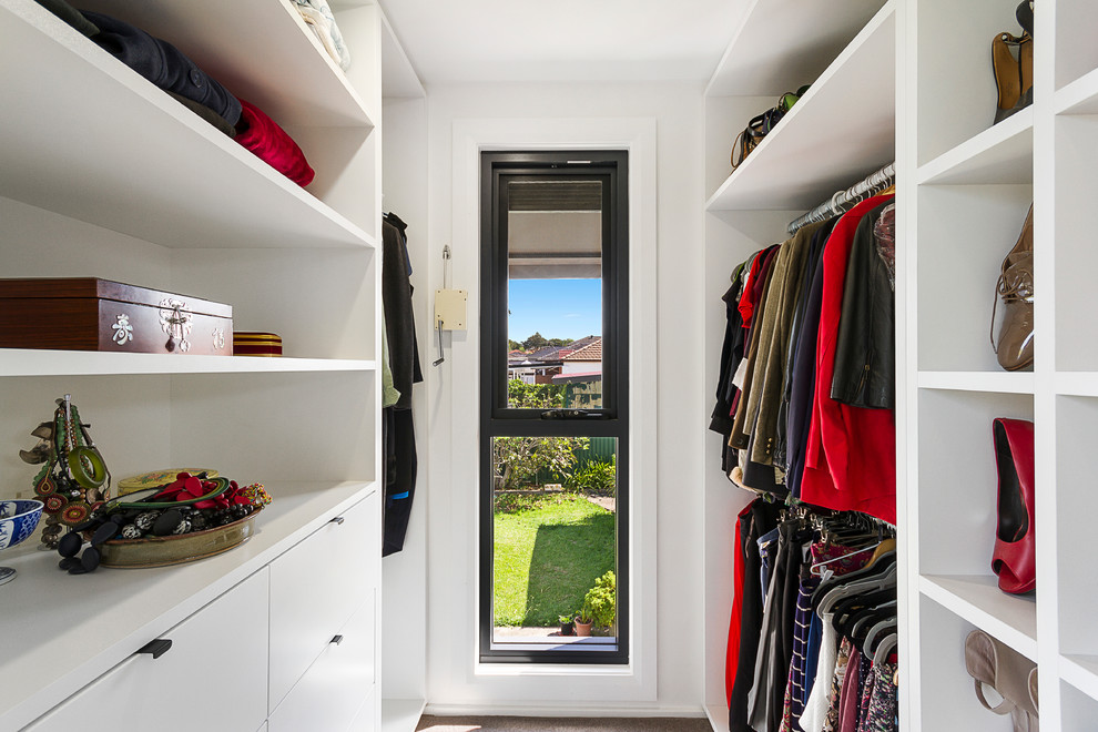 Idées déco pour un dressing contemporain neutre avec un placard à porte plane et des portes de placard blanches.