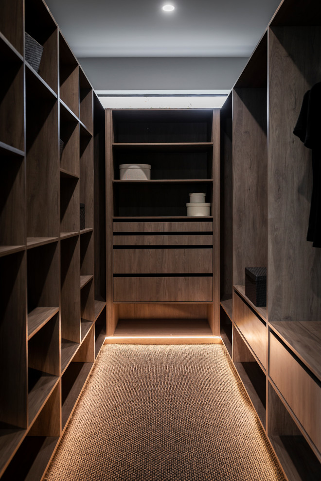 На фото: гардеробная комната среднего размера, унисекс в стиле модернизм с светлыми деревянными фасадами, ковровым покрытием и серым полом