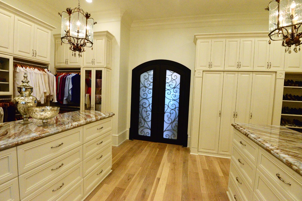 Exemple d'un très grand dressing room chic neutre avec un placard avec porte à panneau encastré, des portes de placard beiges, parquet clair et un sol beige.