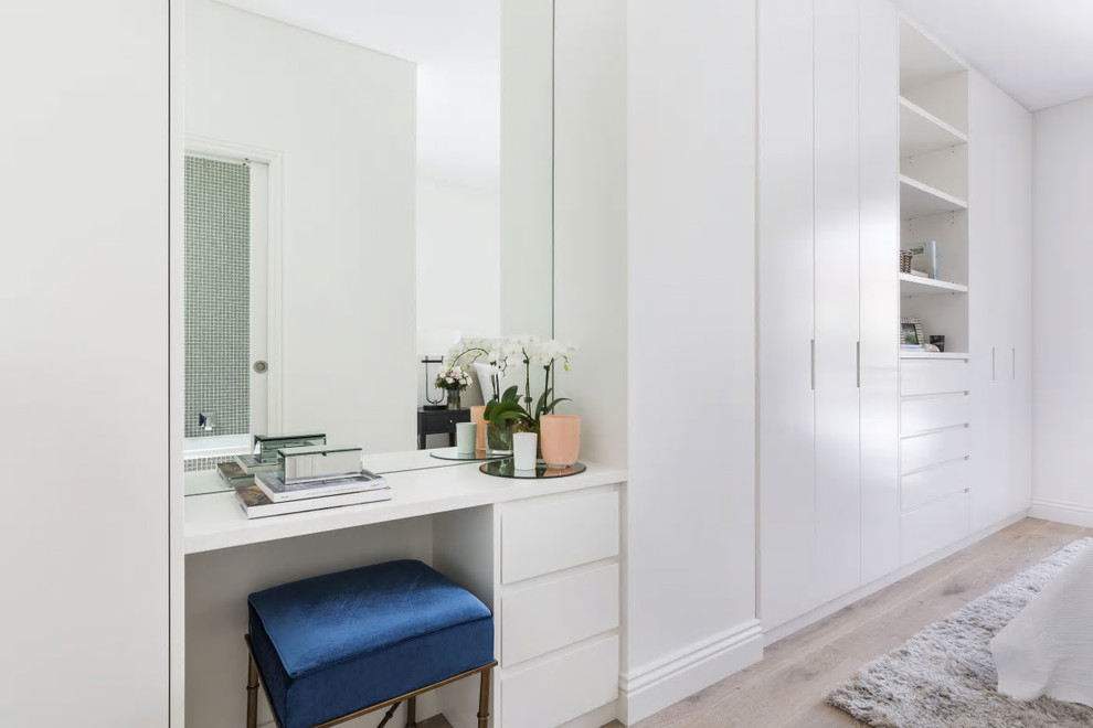 Aménagement d'un dressing et rangement contemporain neutre avec un placard à porte plane, des portes de placard blanches, parquet clair et un sol beige.