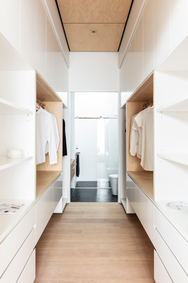 Пример оригинального дизайна: гардеробная комната унисекс в современном стиле с плоскими фасадами, белыми фасадами, светлым паркетным полом и бежевым полом