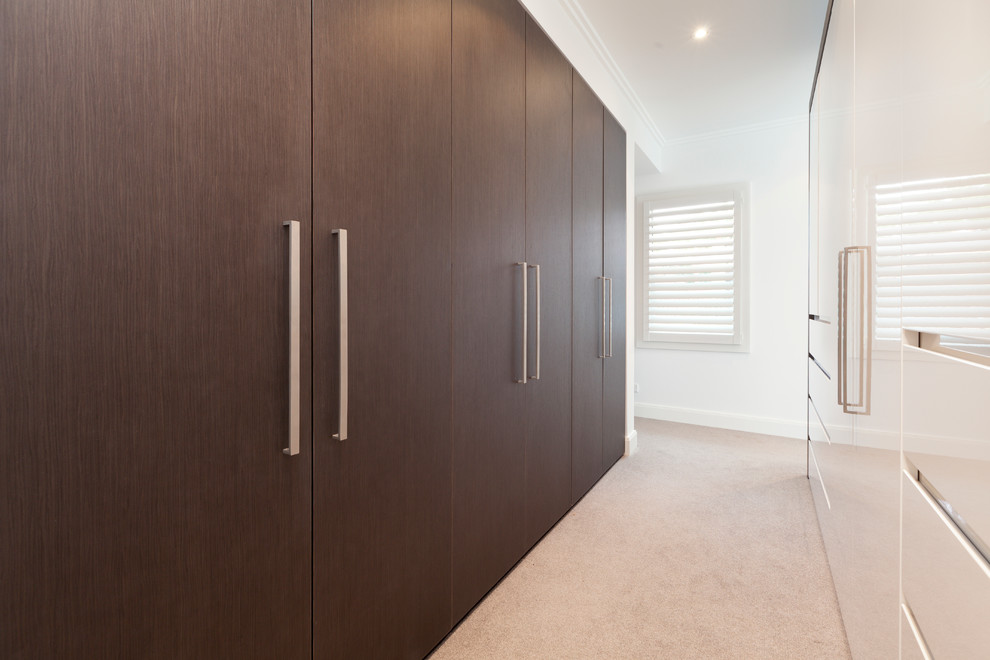 На фото: гардеробная комната унисекс в современном стиле с плоскими фасадами, коричневыми фасадами и ковровым покрытием с