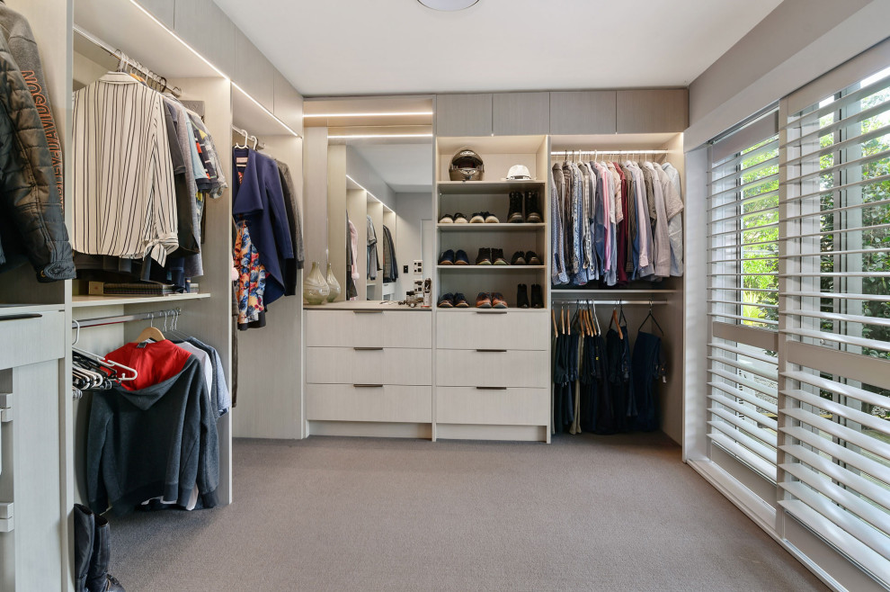 Inspiration for an urban gender neutral walk-in wardrobe in Hamilton with open cabinets, light wood cabinets and carpet.