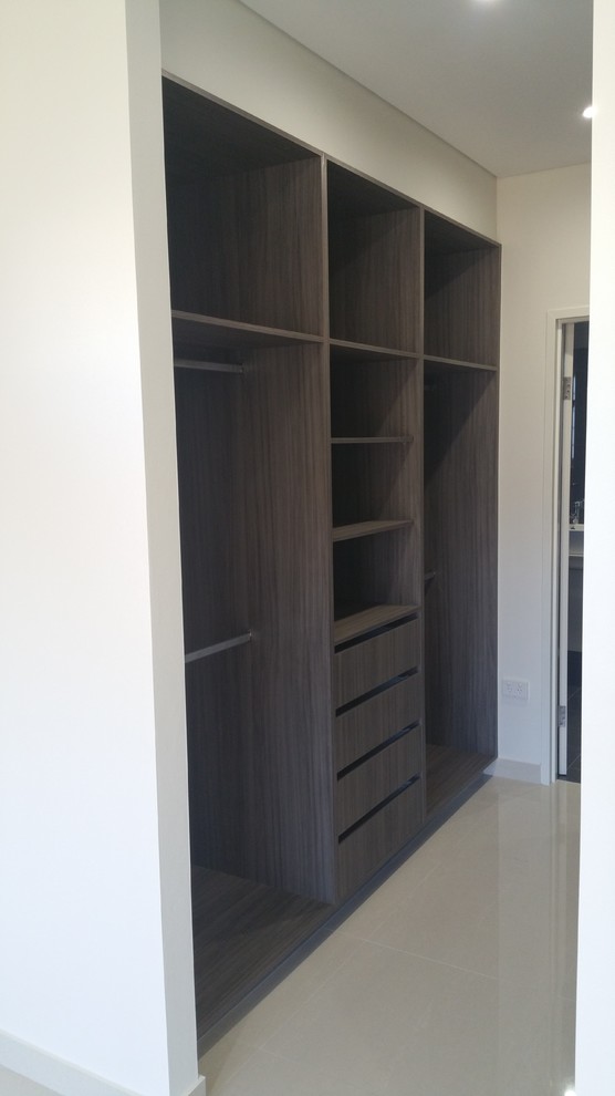 Modelo de armario vestidor unisex moderno de tamaño medio con armarios abiertos, puertas de armario de madera oscura y suelo de baldosas de porcelana