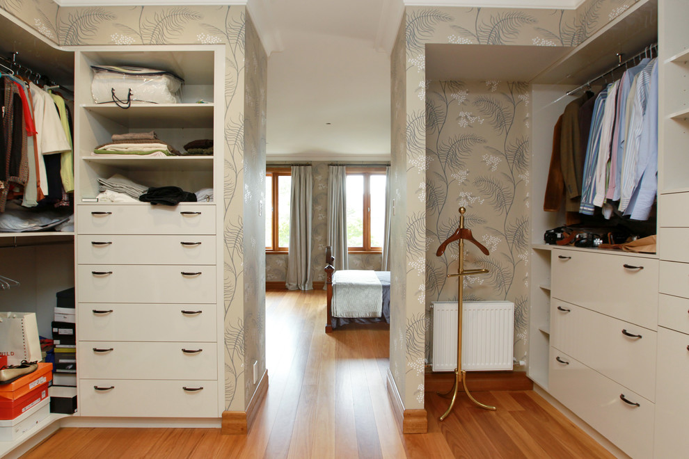 Example of a large classic dark wood floor walk-in closet design in Melbourne with flat-panel cabinets and beige cabinets