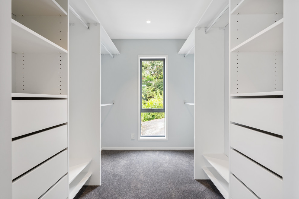 Mittelgroßer, Neutraler Moderner Begehbarer Kleiderschrank mit flächenbündigen Schrankfronten, weißen Schränken, Teppichboden und grauem Boden in Auckland