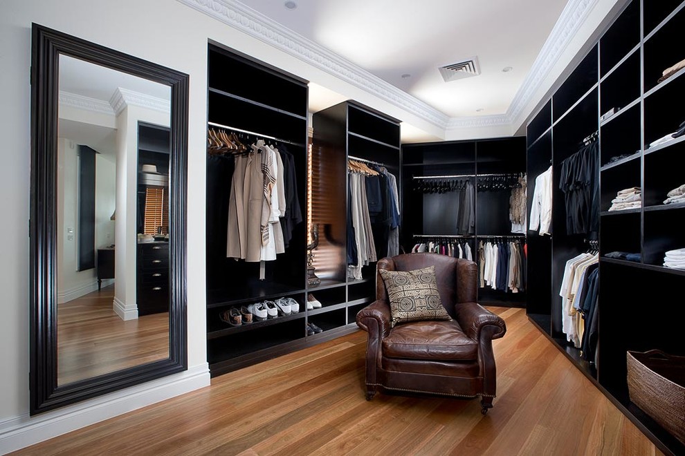 Imagen de vestidor unisex clásico renovado con armarios abiertos, puertas de armario negras, suelo de madera en tonos medios y suelo marrón