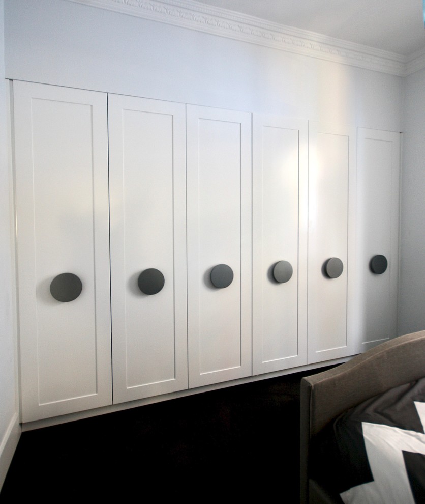 Exemple d'un grand placard dressing chic neutre avec un placard à porte shaker, des portes de placard blanches, moquette et un sol noir.