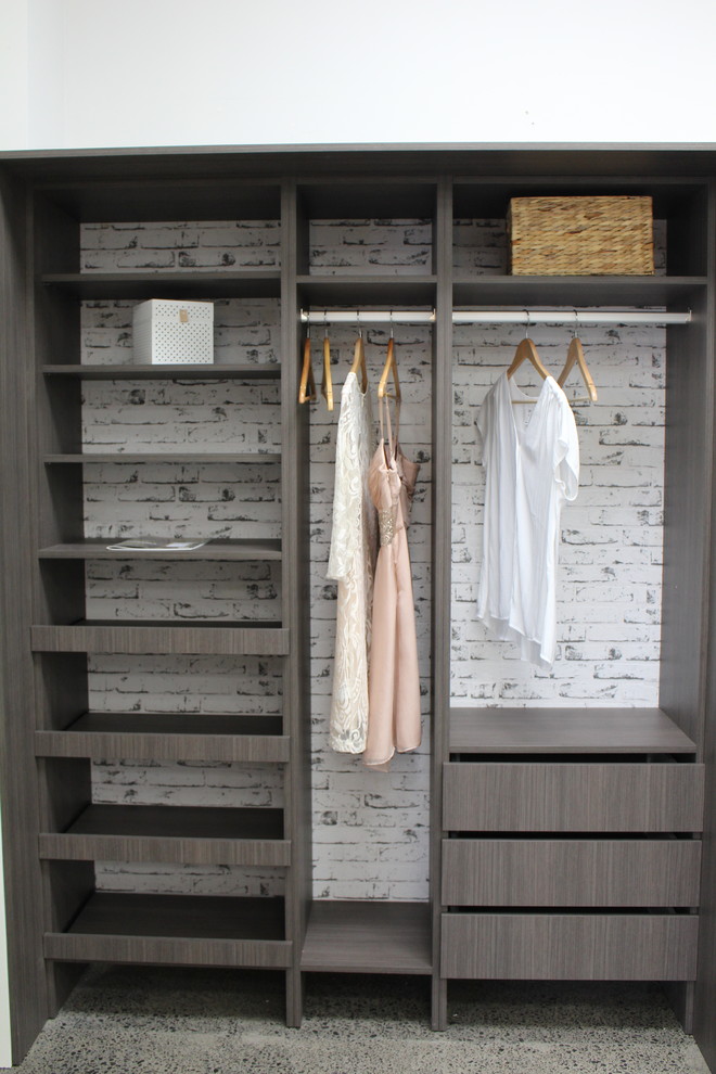 Ispirazione per una cabina armadio unisex minimalista di medie dimensioni con ante in legno bruno
