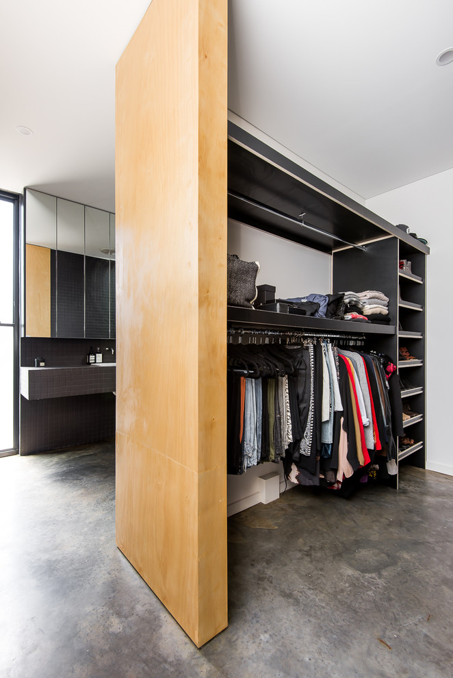 Modelo de armario vestidor unisex moderno pequeño con armarios abiertos, puertas de armario negras y suelo de cemento