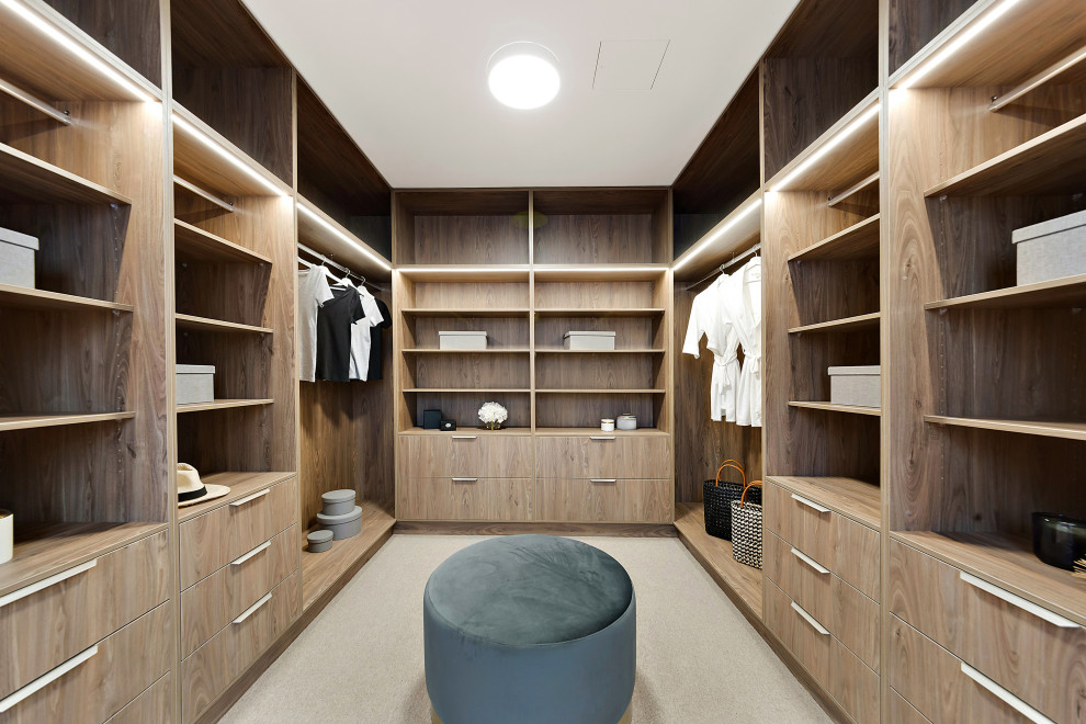 This is an example of a mid-sized contemporary gender-neutral dressing room in Canberra - Queanbeyan with open cabinets, medium wood cabinets, carpet and grey floor.