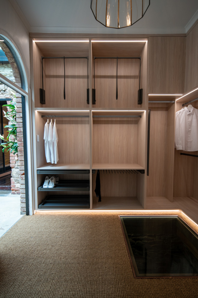 Idee per una cabina armadio design con nessun'anta, ante in legno chiaro e pavimento marrone