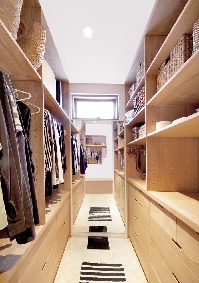 Imagen de armario vestidor unisex minimalista pequeño con puertas de armario de madera clara, suelo de travertino y armarios con paneles lisos
