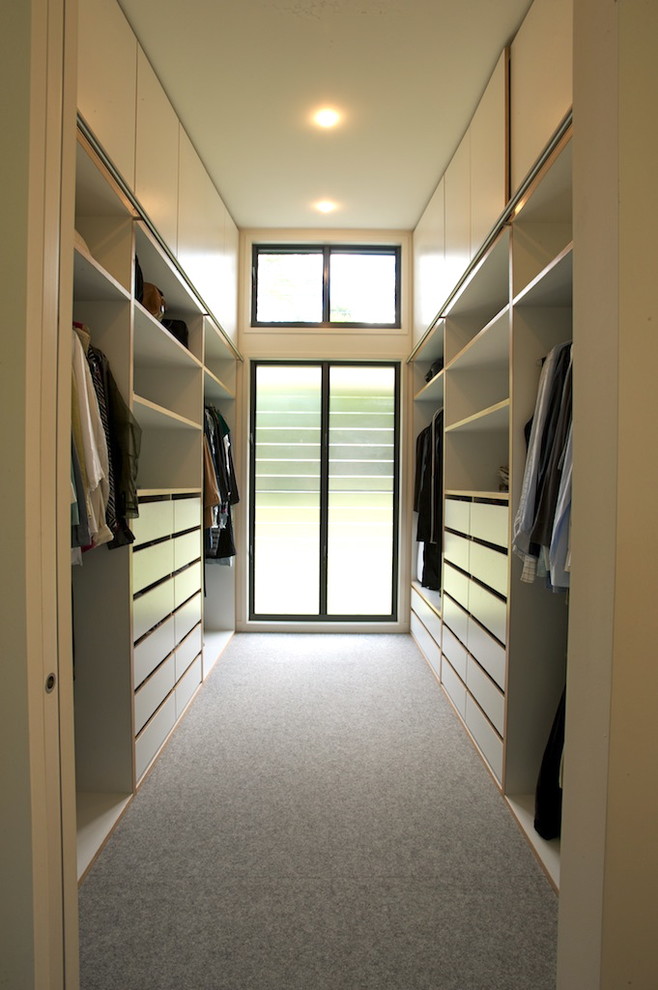 На фото: гардеробная комната среднего размера, унисекс в современном стиле с белыми фасадами, ковровым покрытием и плоскими фасадами