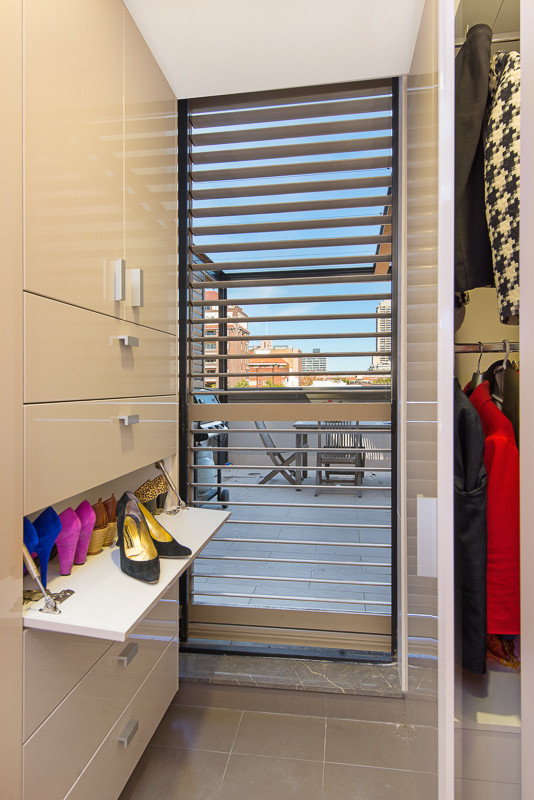 Diseño de armario vestidor de mujer moderno con armarios con paneles lisos, puertas de armario beige y suelo de baldosas de porcelana