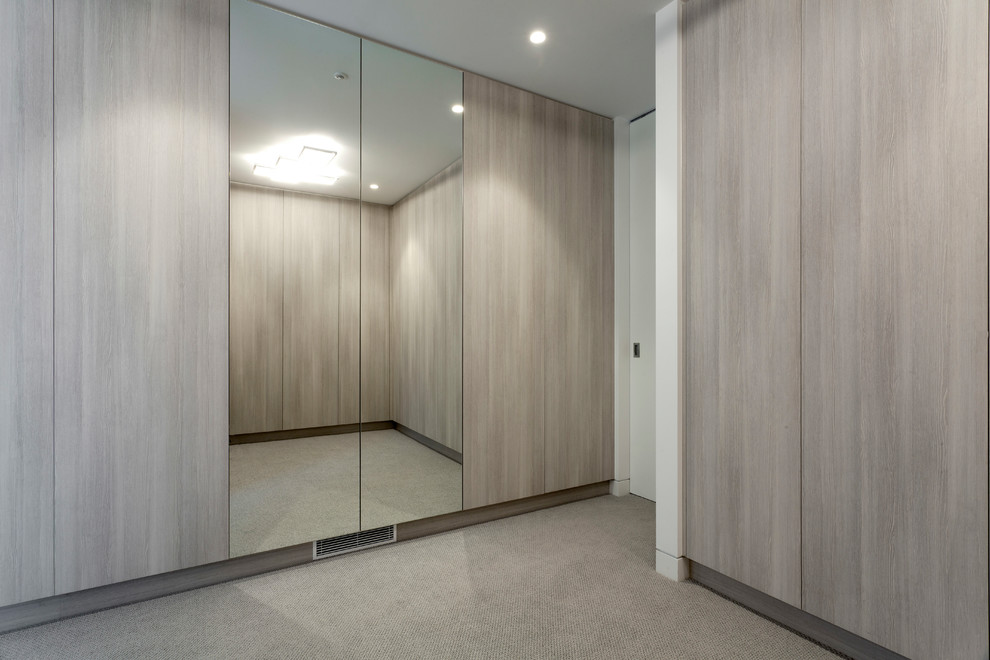 Photo of an expansive modern gender neutral walk-in wardrobe in Melbourne with flat-panel cabinets, distressed cabinets and carpet.