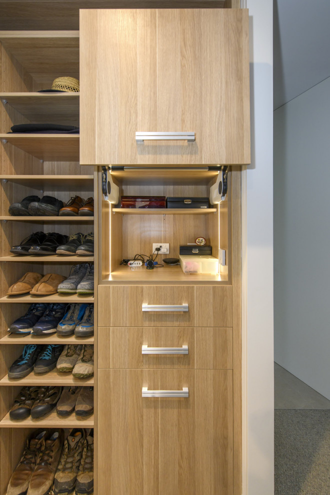 Diseño de armario vestidor unisex minimalista extra grande con armarios con paneles lisos, puertas de armario de madera clara, moqueta y suelo gris