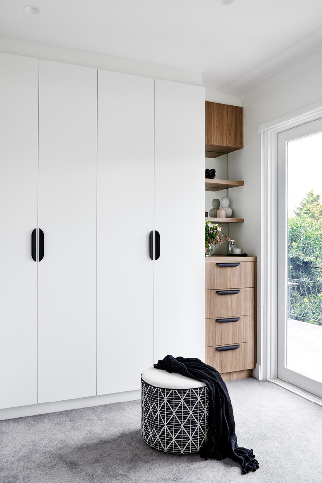 This is an example of a contemporary walk-in wardrobe in Sydney with flat-panel cabinets, white cabinets, carpet and grey floors.