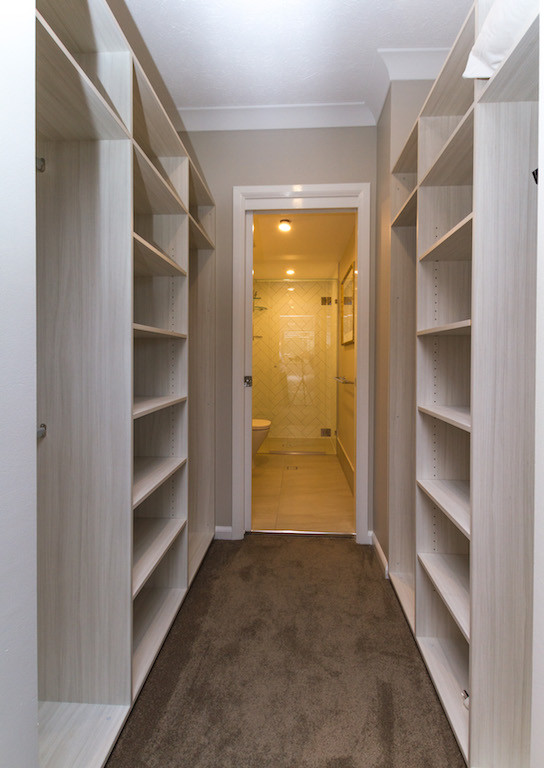 Modelo de armario vestidor unisex tradicional renovado de tamaño medio con armarios abiertos, puertas de armario de madera clara, moqueta y suelo beige