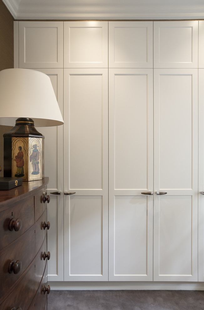 На фото: гардеробная комната среднего размера в классическом стиле с фасадами в стиле шейкер, белыми фасадами и ковровым покрытием для мужчин с