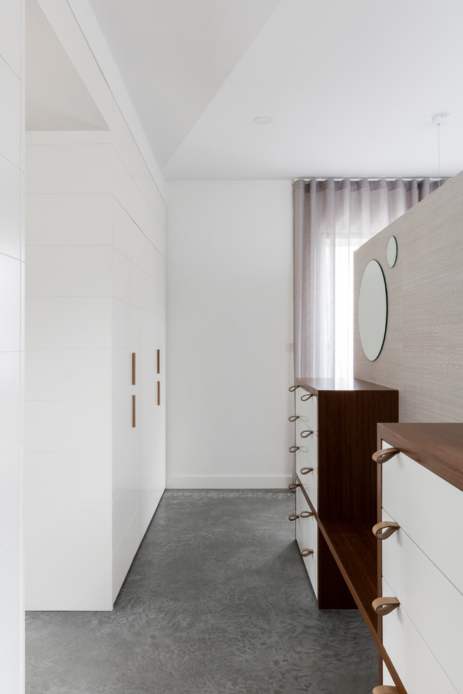 Inspiration pour un dressing room design neutre avec un placard à porte plane, des portes de placard blanches, sol en béton ciré et un sol gris.