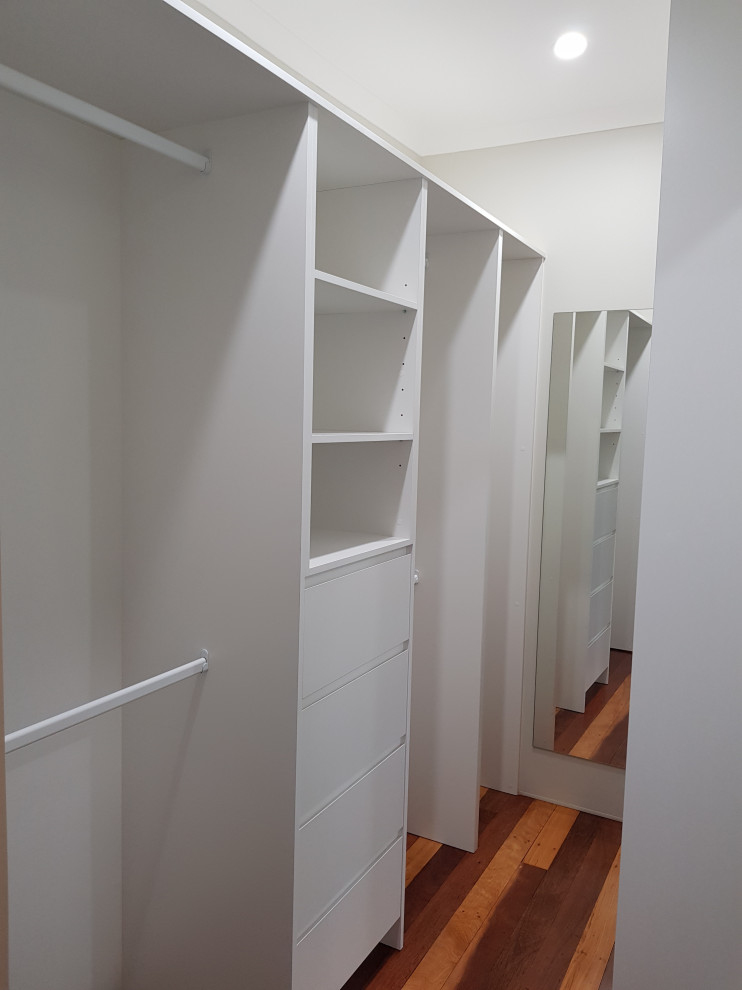 Diseño de armario y vestidor contemporáneo pequeño con puertas de armario blancas y suelo laminado