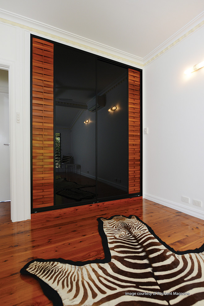 Diseño de armario unisex exótico con armarios tipo vitrina, puertas de armario de madera oscura y suelo de madera en tonos medios