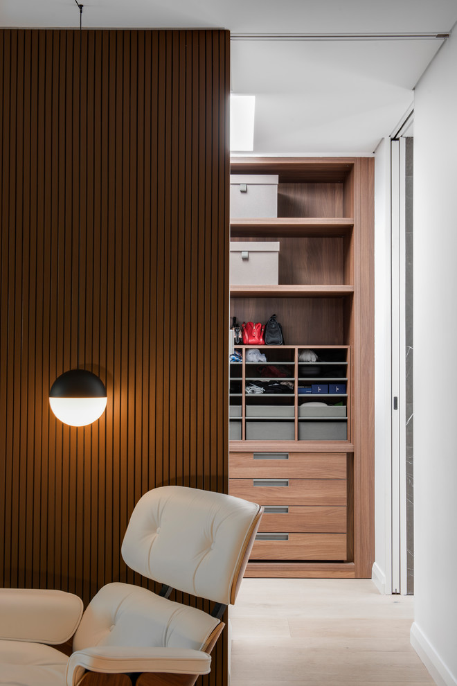 На фото: гардеробная комната среднего размера в стиле модернизм с открытыми фасадами, темными деревянными фасадами и светлым паркетным полом с