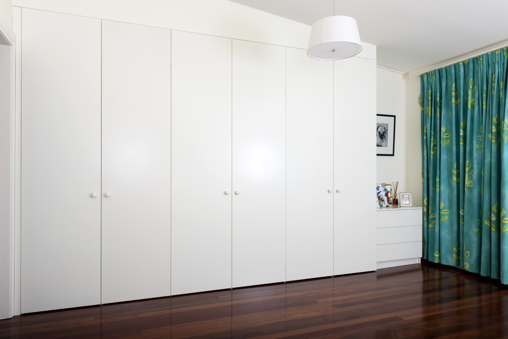 Ejemplo de armario unisex tradicional de tamaño medio con puertas de armario blancas, suelo de madera oscura y armarios con paneles lisos