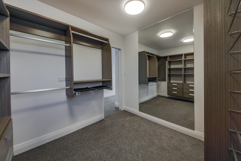 Inspiration for a medium sized coastal gender neutral walk-in wardrobe in Wellington with open cabinets, dark wood cabinets, carpet and grey floors.