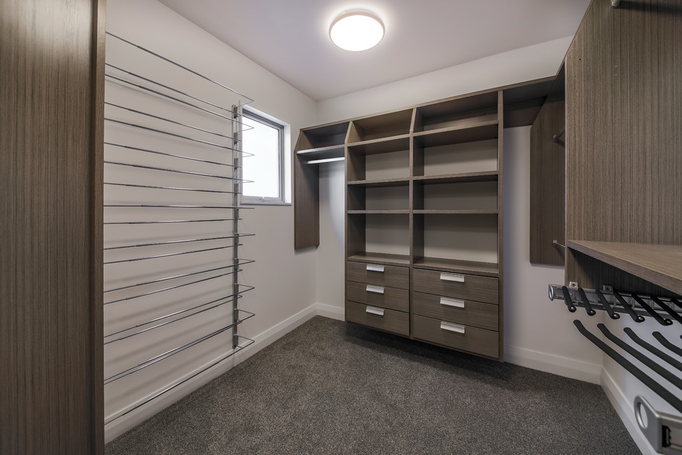Inspiration for a medium sized beach style gender neutral walk-in wardrobe in Wellington with open cabinets, dark wood cabinets, carpet and grey floors.