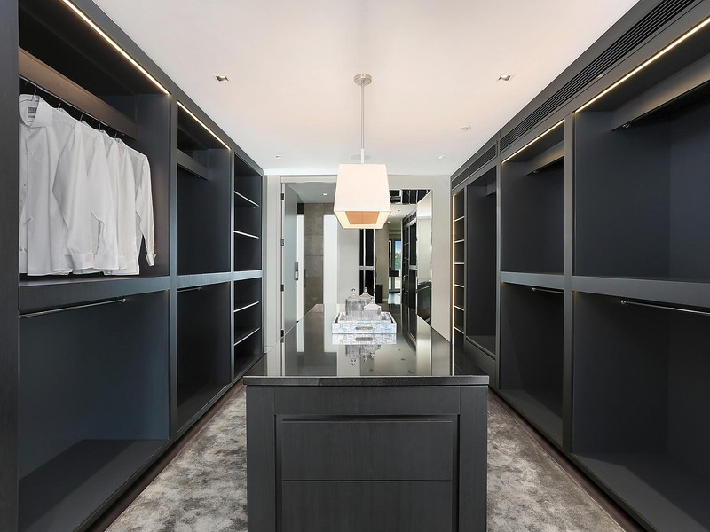 Diseño de armario vestidor unisex actual grande con puertas de armario negras, moqueta y suelo gris