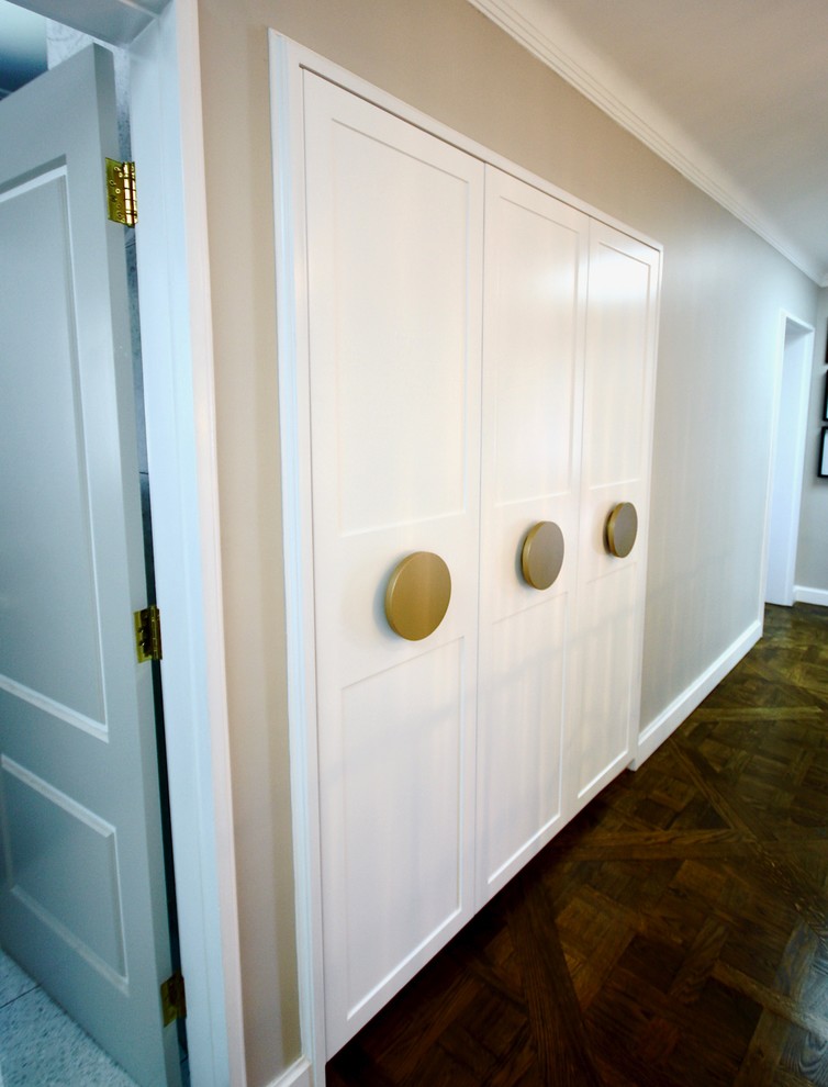 Immagine di un grande armadio o armadio a muro unisex chic con ante con riquadro incassato, ante bianche, pavimento in legno massello medio e pavimento marrone