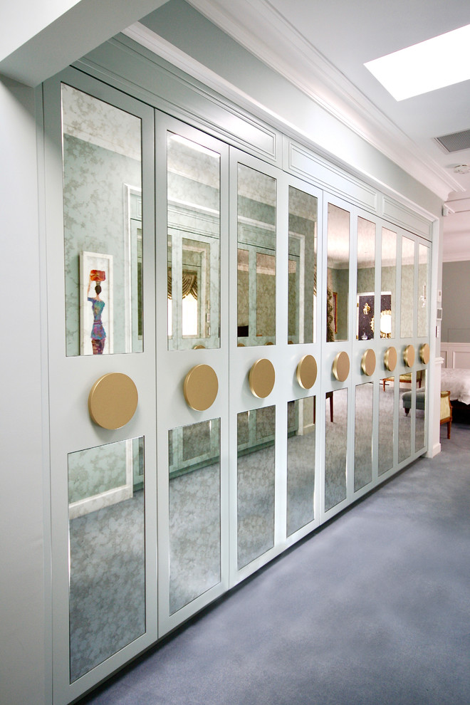Aménagement d'un grand dressing room classique neutre avec un placard à porte vitrée, des portes de placard bleues, un sol en bois brun et un sol gris.