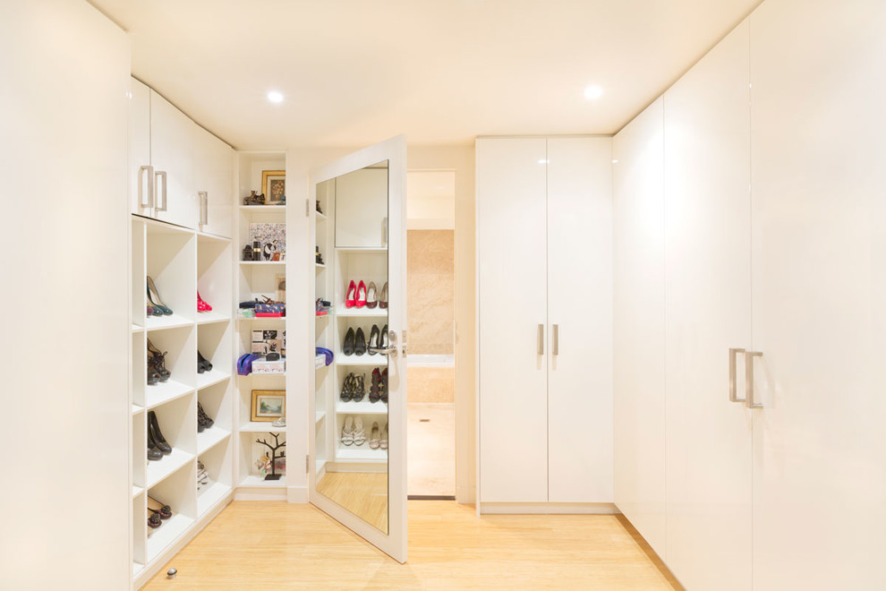 Example of a small minimalist women's light wood floor and brown floor walk-in closet design in Melbourne with flat-panel cabinets and white cabinets