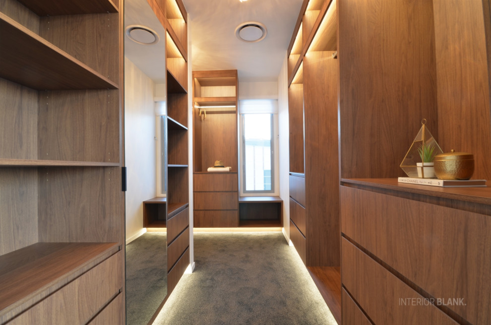 Aménagement d'un grand dressing room contemporain en bois brun neutre avec un placard à porte plane, moquette et un sol gris.