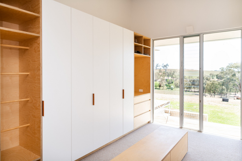 Photo of a medium sized contemporary dressing room in Other with light wood cabinets, carpet and beige floors.