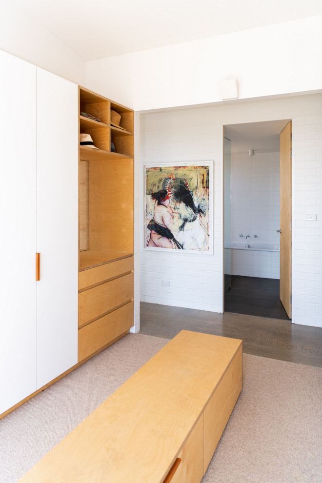 Ispirazione per uno spazio per vestirsi minimal di medie dimensioni con ante in legno chiaro, moquette e pavimento beige