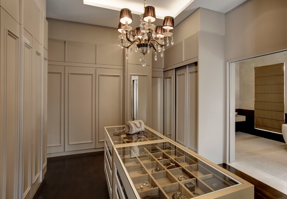 Inspiration for a transitional women's dark wood floor and brown floor walk-in closet remodel in Singapore with recessed-panel cabinets and beige cabinets