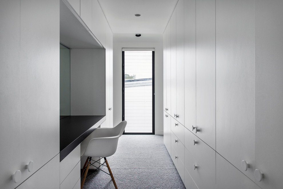 Пример оригинального дизайна: большая гардеробная комната унисекс в современном стиле с белыми фасадами и ковровым покрытием