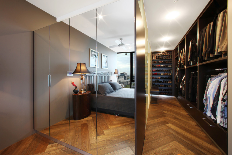 Foto de armario vestidor unisex moderno de tamaño medio con suelo de madera en tonos medios, armarios abiertos y puertas de armario de madera oscura